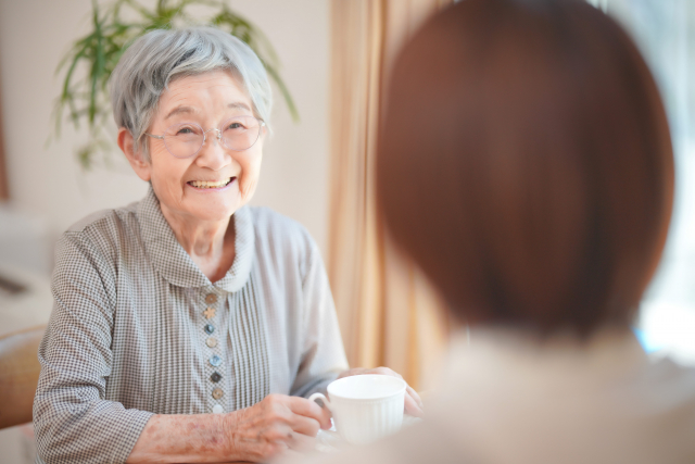 お茶を飲みながら微笑む高齢女性