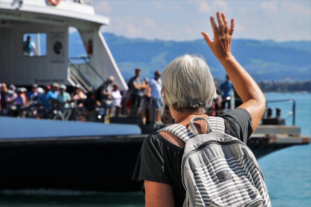 去る船に手を振る高齢女性