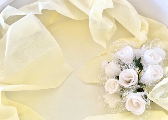 プレゼント包装紙と白いバラの花束
