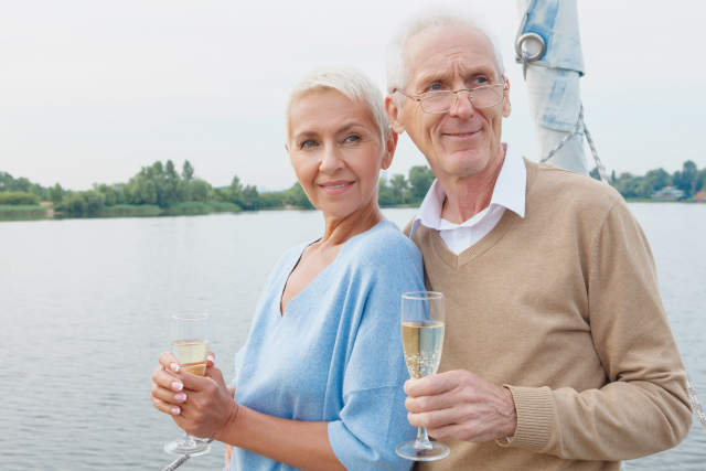 ヨットに乗ってシャンパンを飲んでいる老夫婦