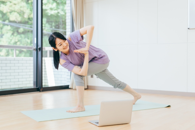 自宅でオンラインヨガレッスンを受ける女性