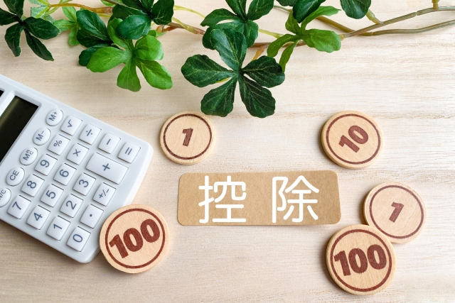 「控除」の文字と電卓とおもちゃの硬貨