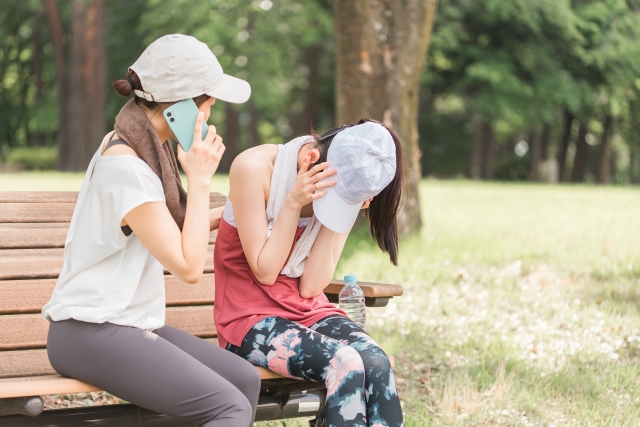 運動中に体調不良になった女性と救急車を呼ぶ人