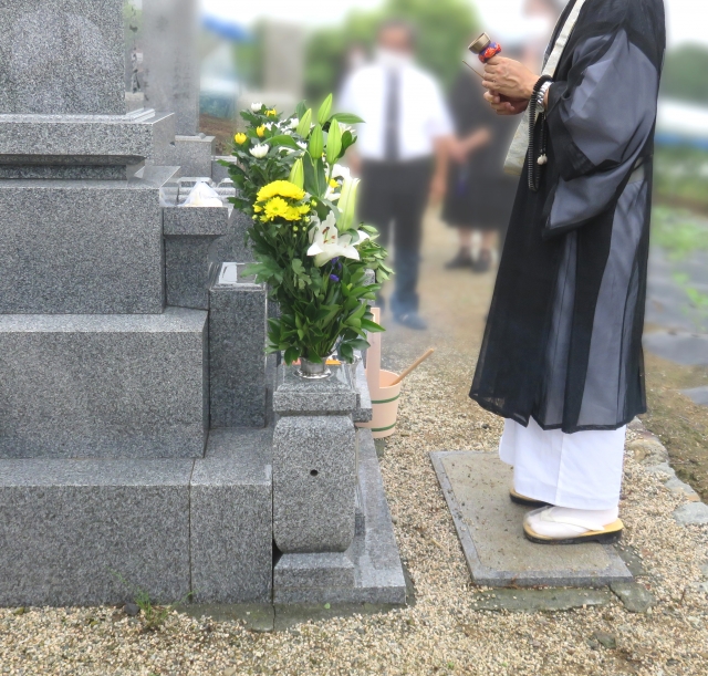 墓前で読経をする僧侶