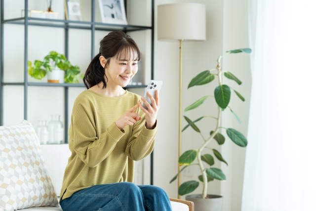 リビングでスマホを見る若い女性