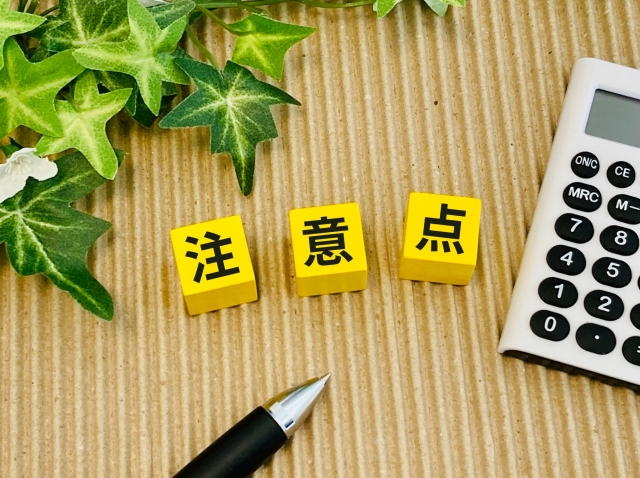 注意点と書かれたブロックと電卓とペン