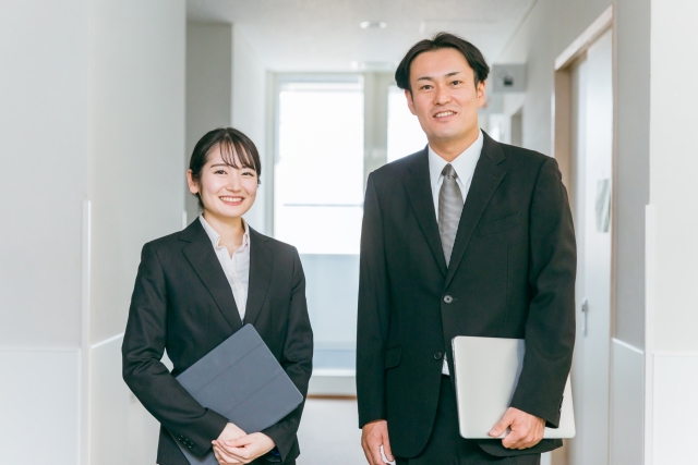 廊下に立つビジネススーツ姿の男女