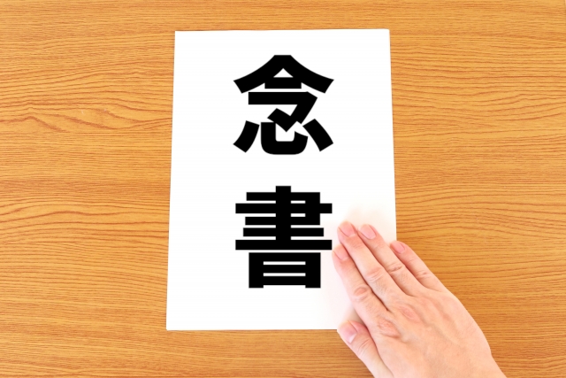 念書と書かれた紙を差し出す手