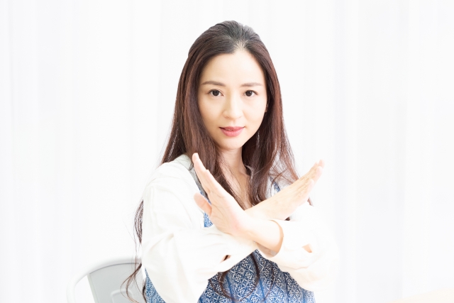 NGのポーズをするリビングで椅子に座っている主婦