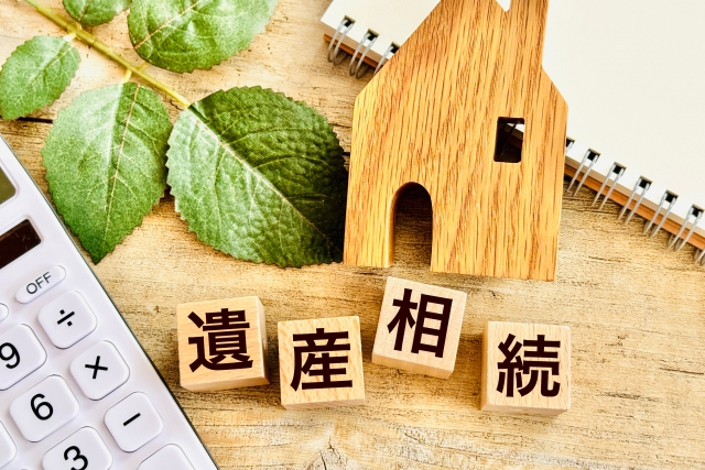 遺産相続と書かれた木のブロックと家の模型と電卓