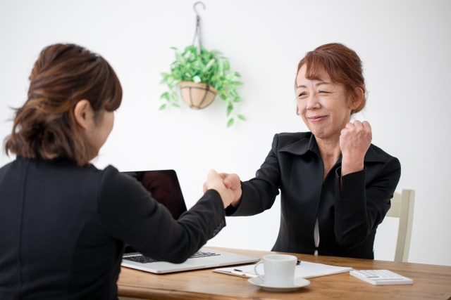 若い女性と拳を合わせるスース姿のシニア女性