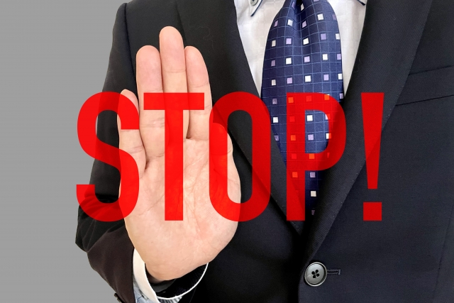ストップの文字とビジネスマンの止める手