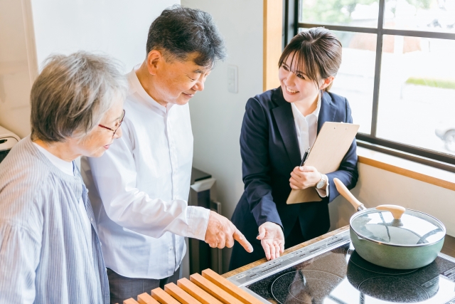 高齢夫婦に内見でITコンロの説明をする女性