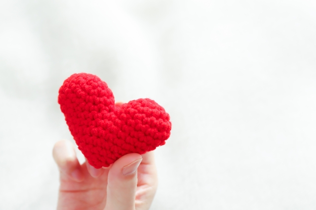 毛糸で編んだハートを持つ手
