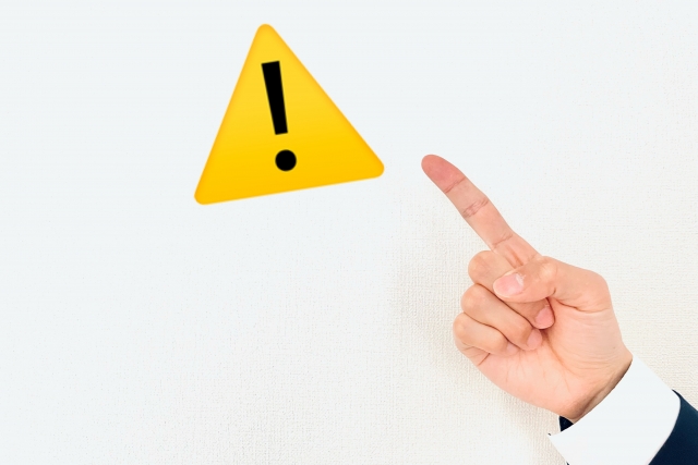 警告マークを指さす男性の手