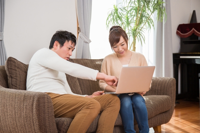 ノートパソコンを見ながら語り合う夫婦