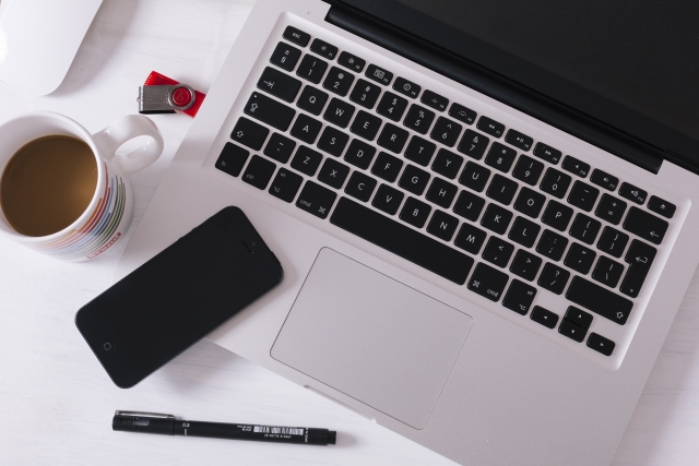 ノートパソコンとスマートフォンとコーヒーと文房具