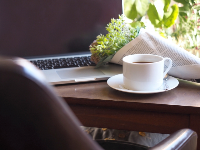机に置かれた花束とコーヒーとノートパソコン