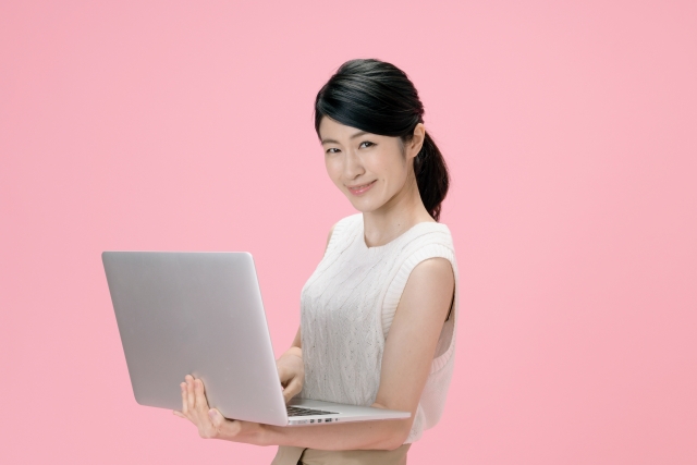 ノートパソコンを持ち微笑む女性