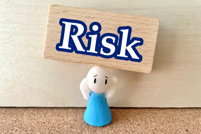Riskの文字の下で頭を抱える人形