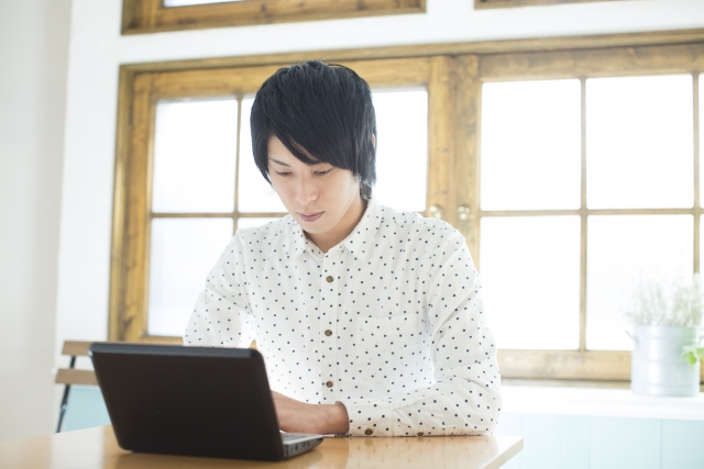 カフェでノートパソコンを開く男性