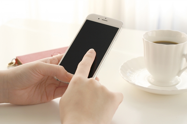 スマホを触る手とコーヒー