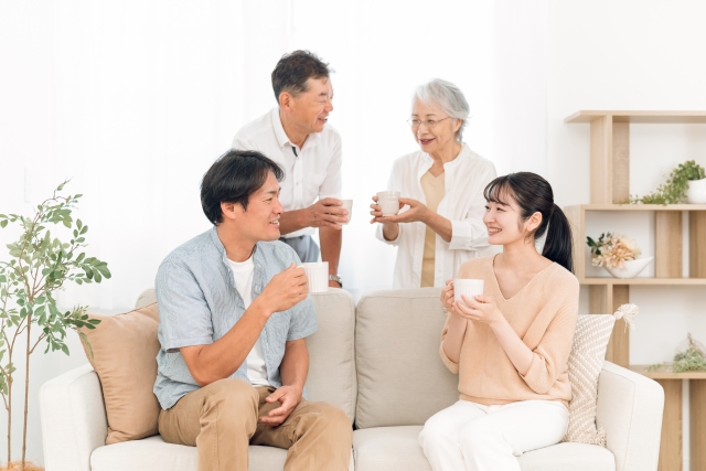 ソファに座って飲み物を飲む家族