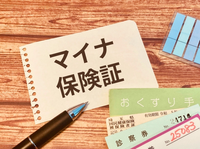 マイナ保険証と書かれたメモと文房具と診察券、おくすり手帳