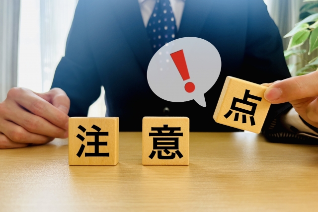 注意点と書かれたブロックを持ち上げる男性